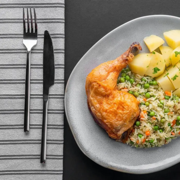 Pilaf de orez cu morcovi și mazăre, servit cu pulpe picante și cartofi natur