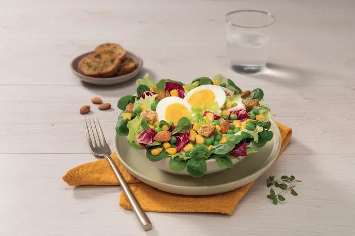 Insalatona a base lollo verde con mais e piselli, uova sode e mandorle