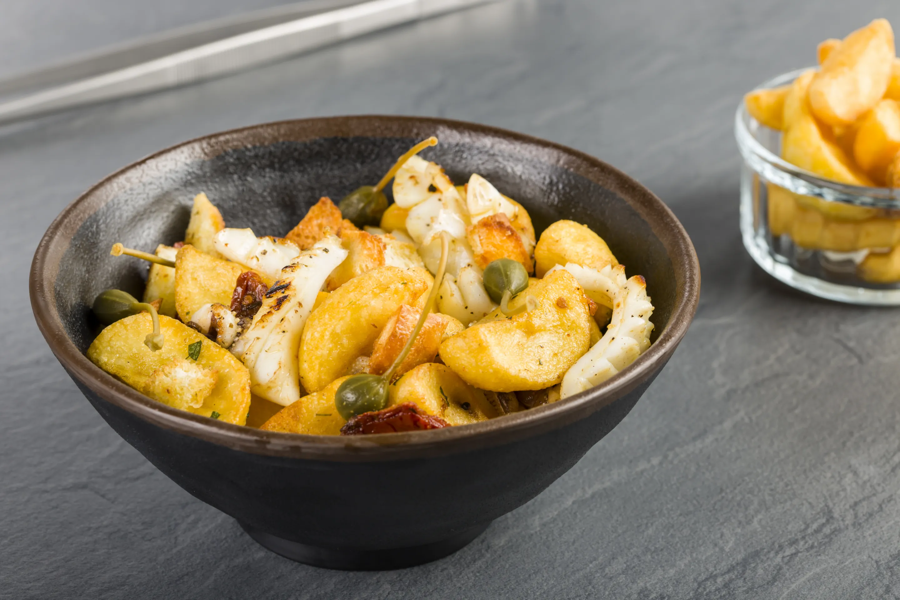 Insalata di patate a spicchi con seppia, pomodoro secco e capperi in fiore