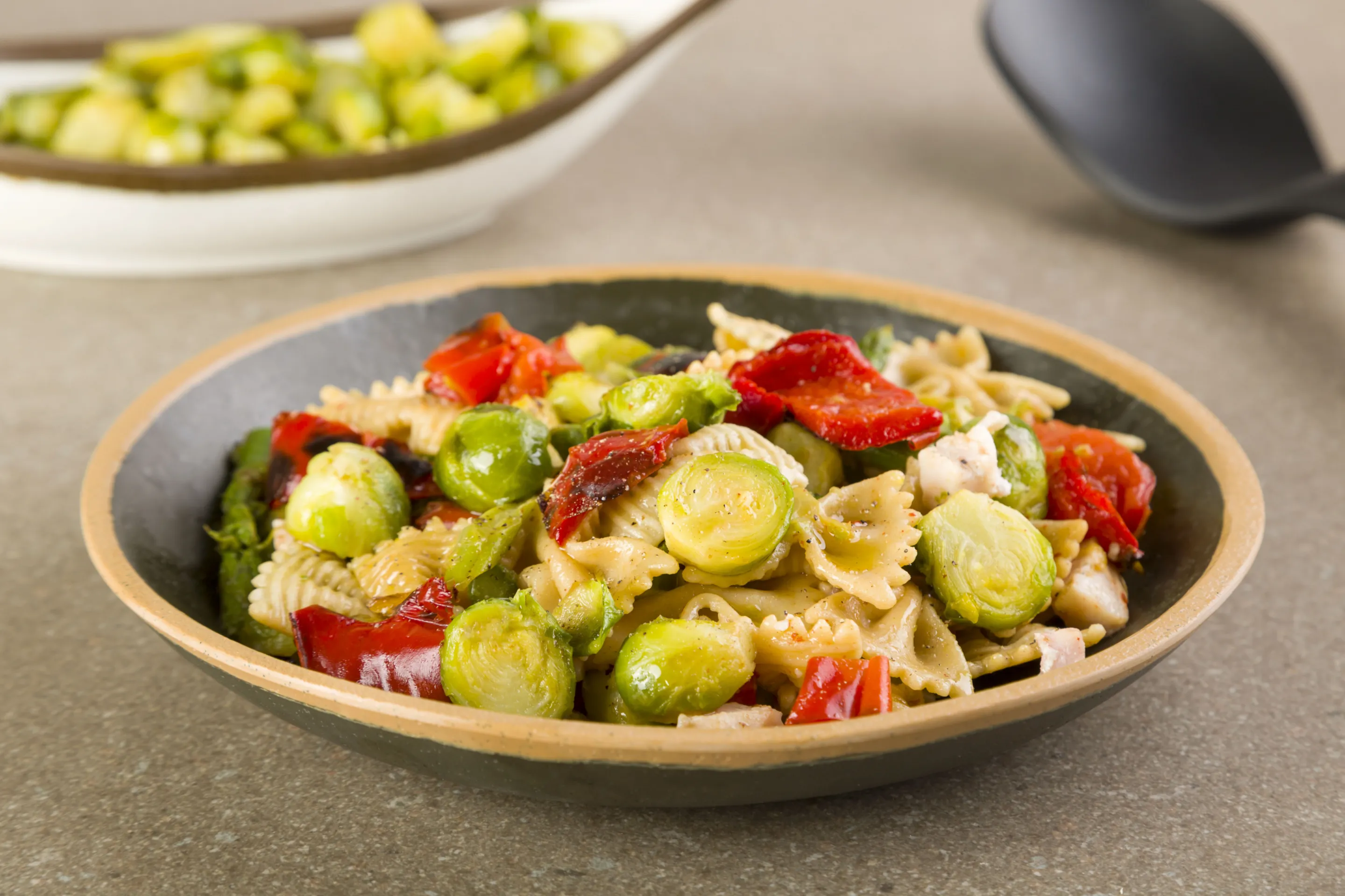 Insalata fredda di farfalle con cavolini bruxelles, asparagi, peperoni rossi e spada affumicato