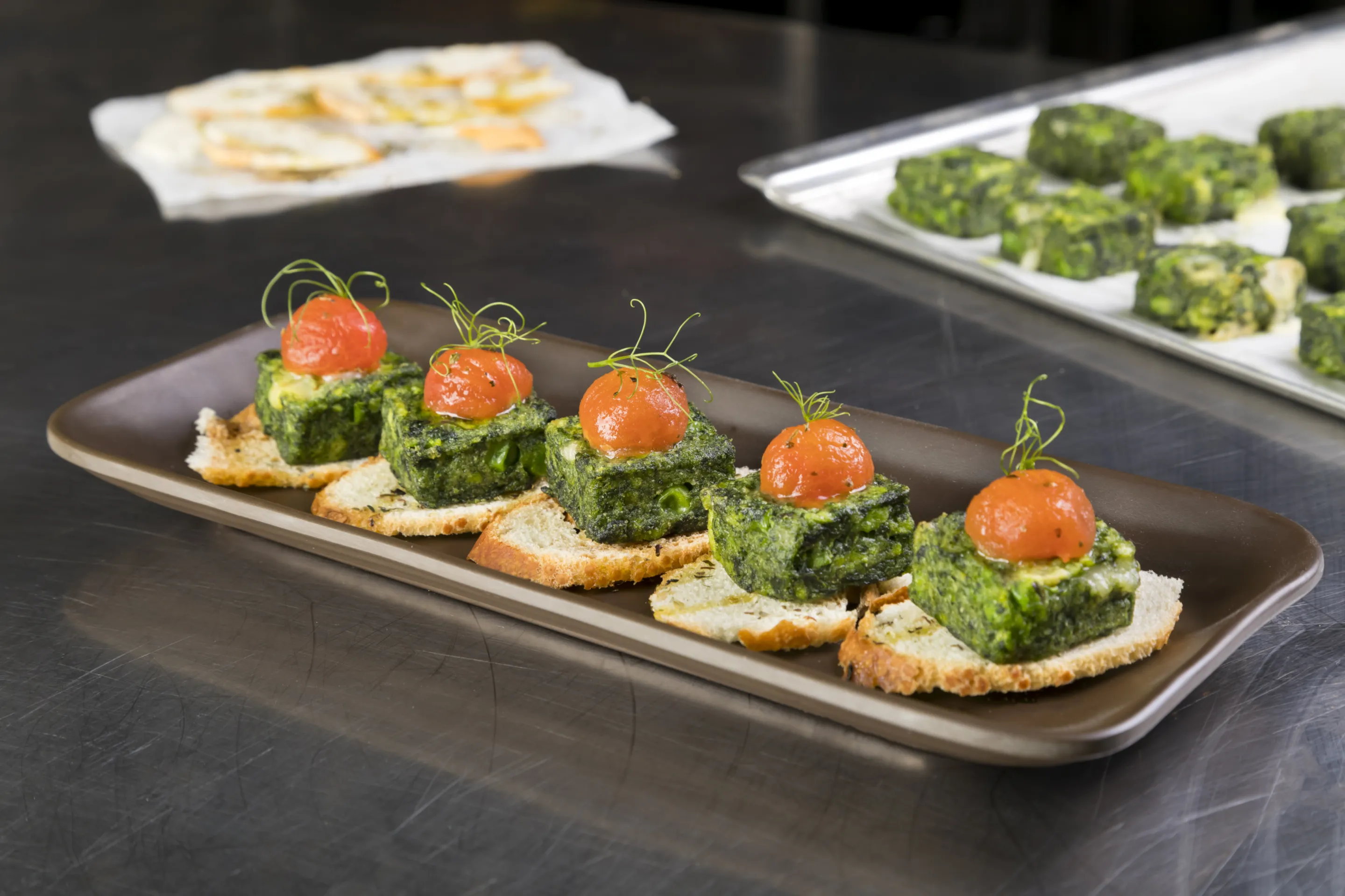 Snack spinaci, piselli e provola con pomodorino candito su pane disidratato