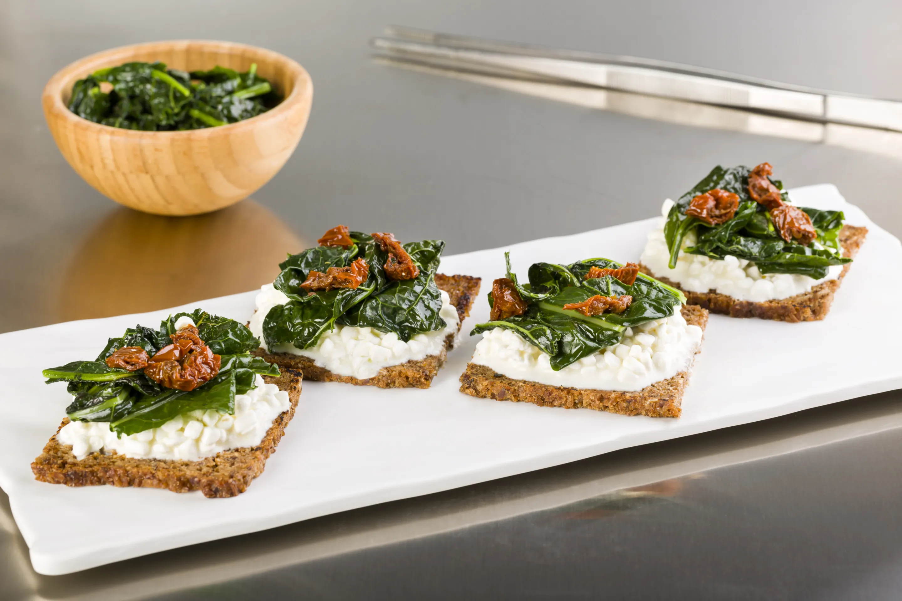 Crostoni di pane di segale con cavolo nero, pomodoro secco e fiocchi di latte