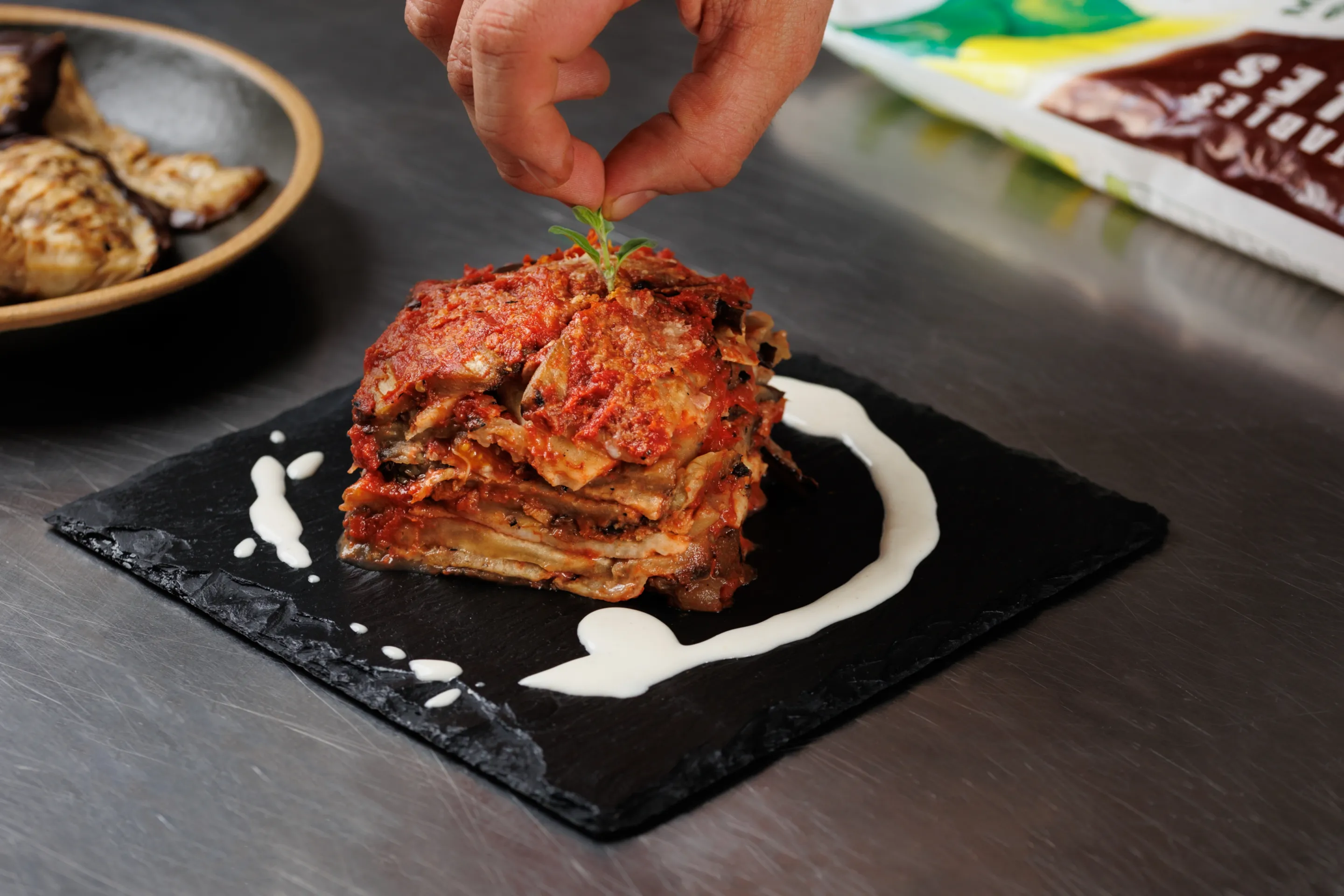 Parmigiana di melanzane grigliate con mozzarella, pomodoro infornato gratinato e basilico