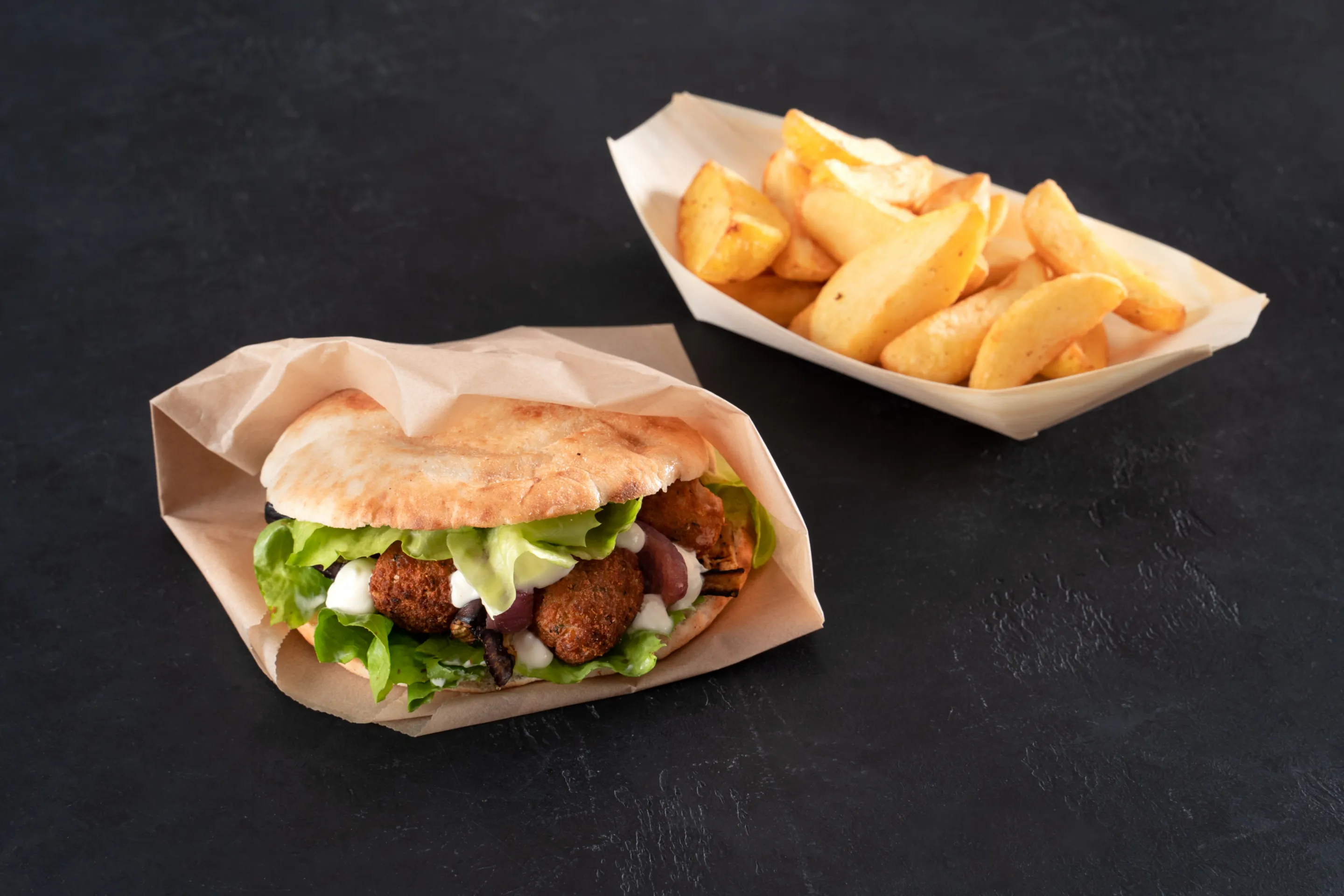 Pane pita con falafel, melanzane, cipolle rosse grigliate e salsa allo yogurt alla tahina e patate a spicchi fritte