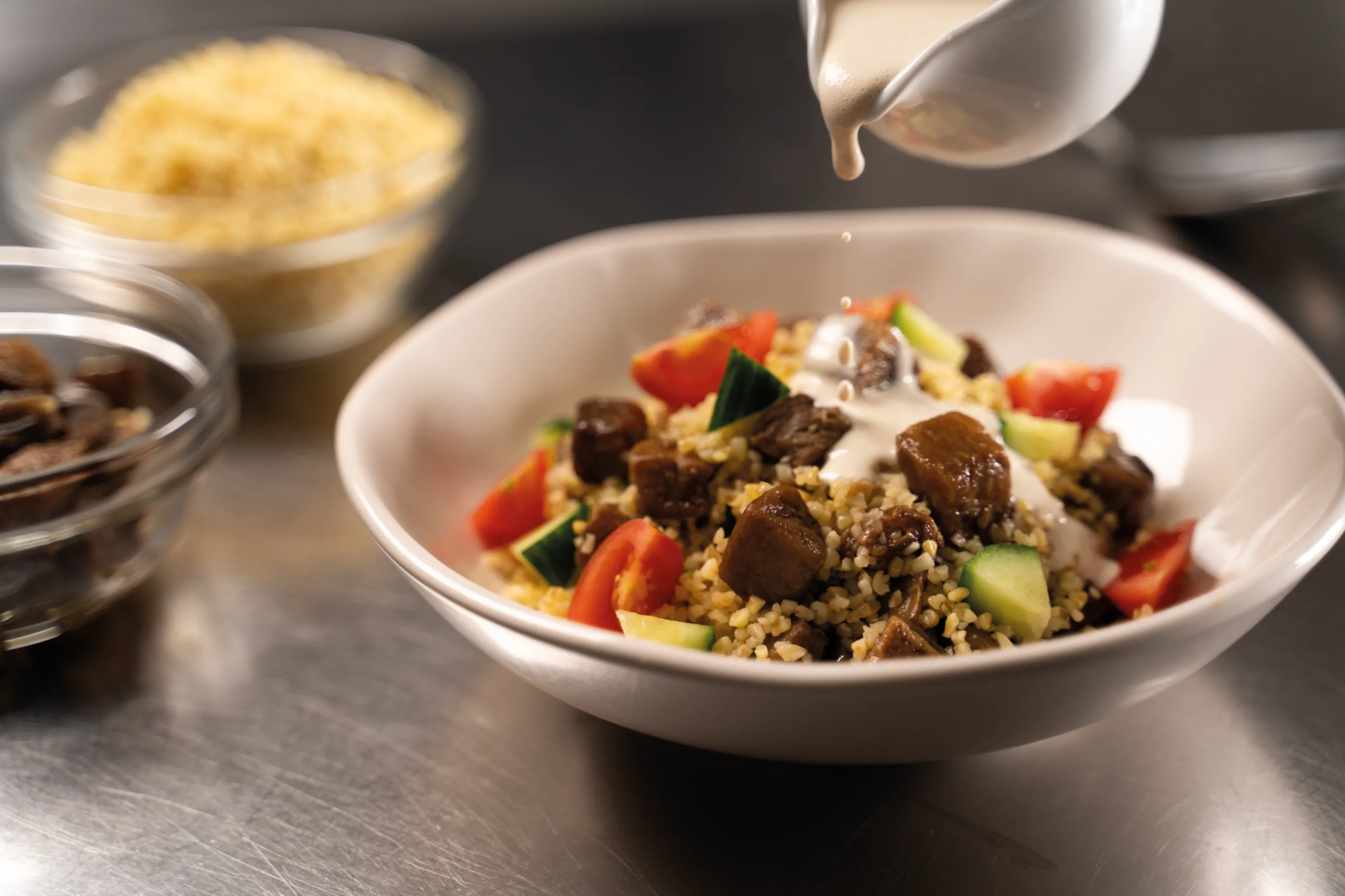 Bowl con Bulgur, Melanzane a cubetti, salsa tahina, pomodorini, cetrioli